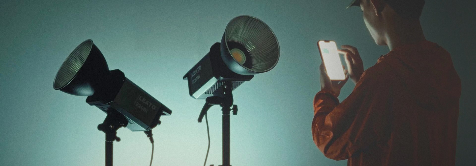 A photographer adjusting two LEATO LED COB lights from the Golden Eagle control app